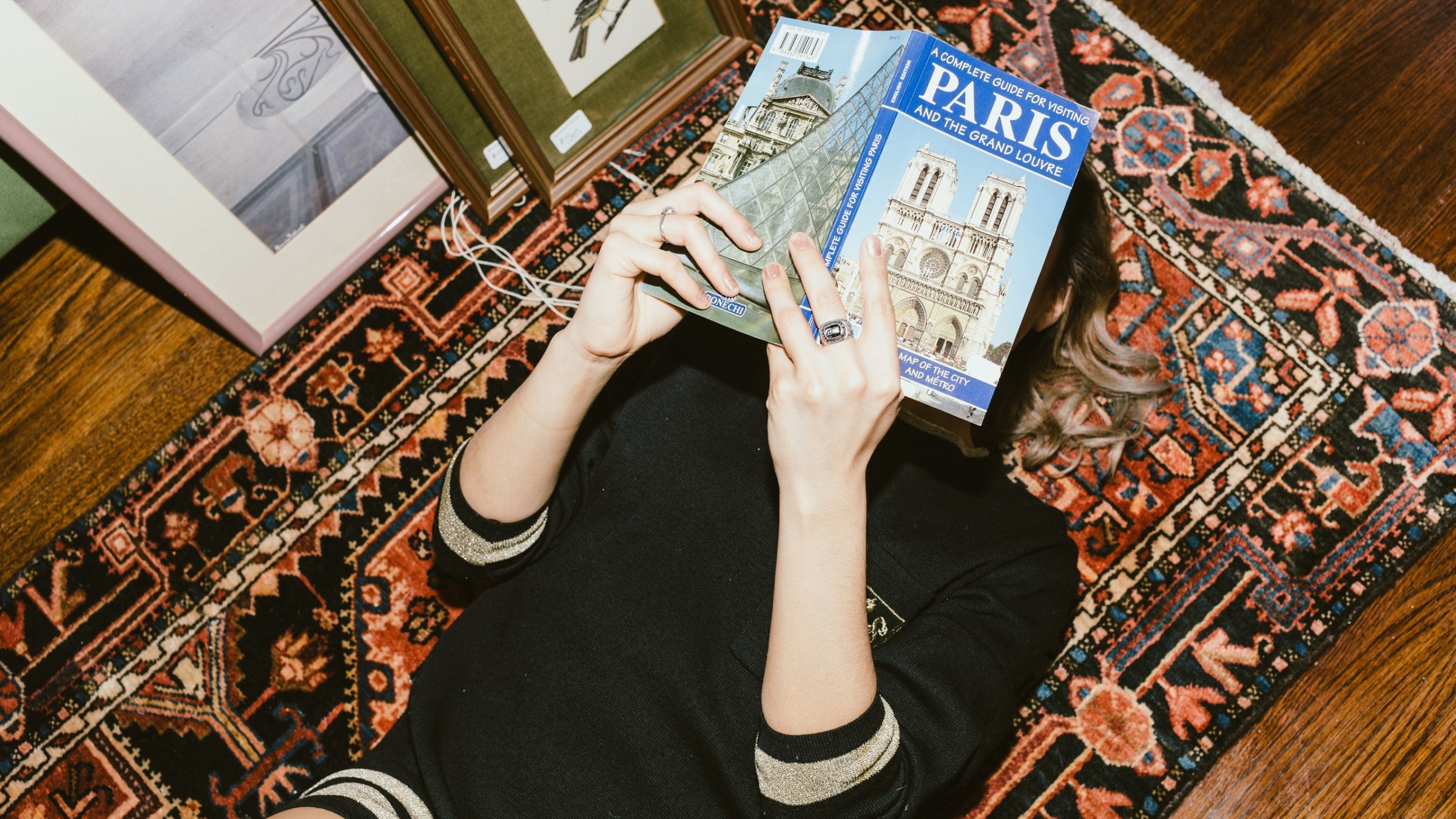 woman reading paris guide on rug