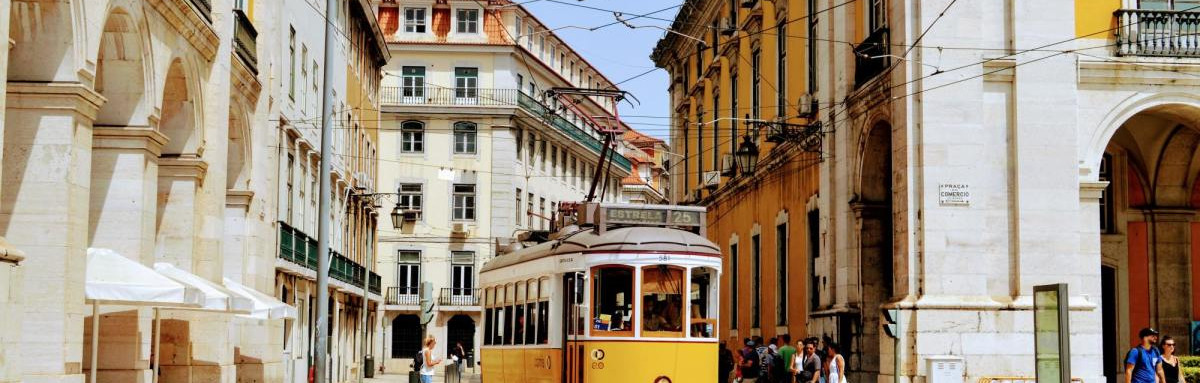 Yellow cable driving through downtown Lisbon on a sunny day.