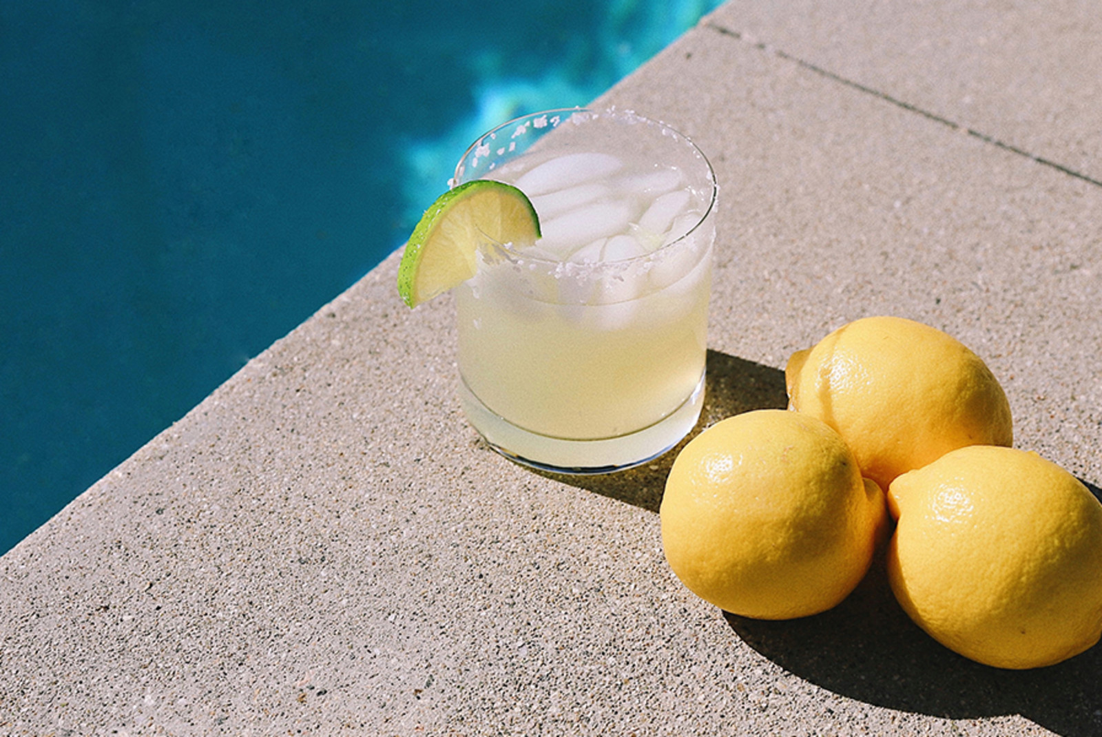 A cocktail with a lime sitting next to a pool in Palm Springs, California. 