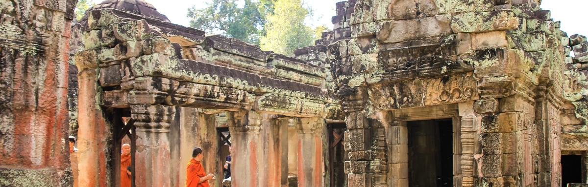 Two monks in orange walking through ancient ruins in Siem Reap.