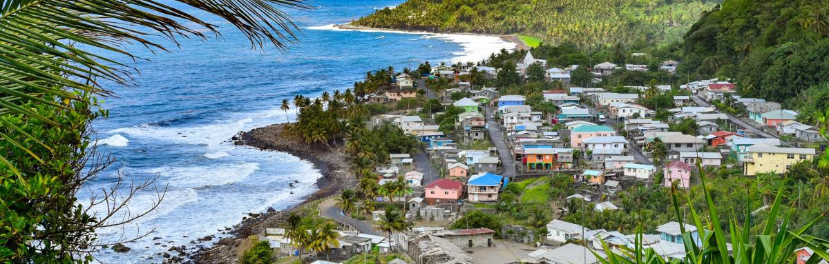 Small village along the ocean surrounded by green hills on a sunny day in St. Vincent