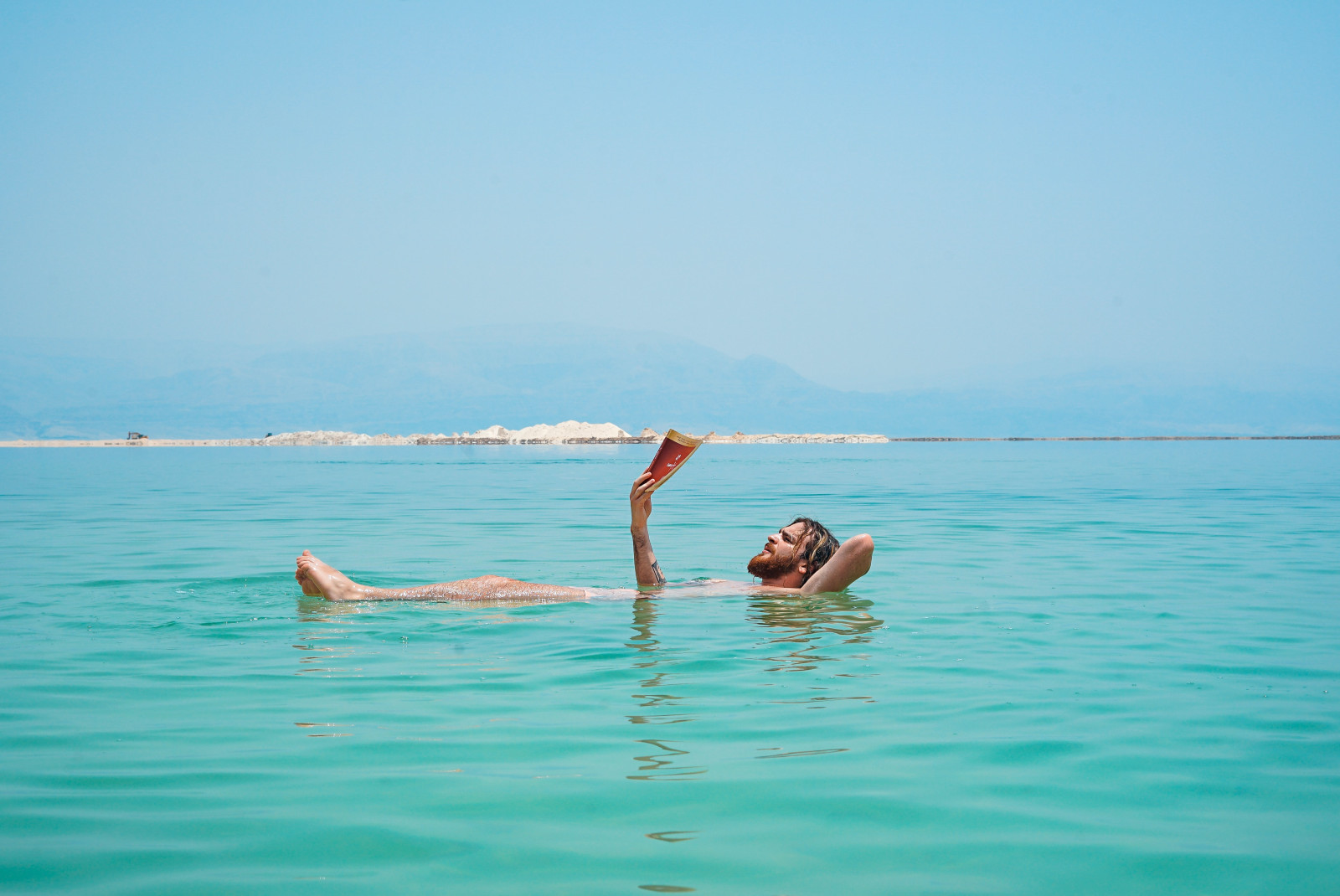 Man floats in the Dead Sea while reading a book